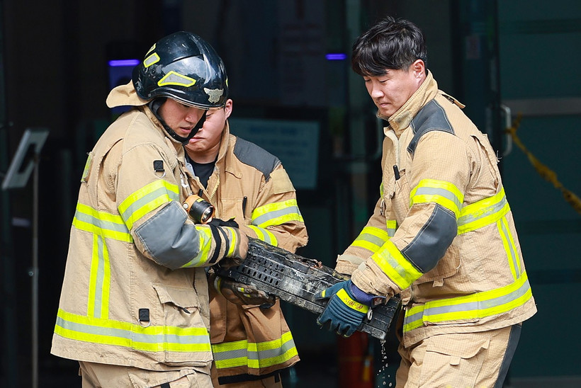 Lính cứu hỏa di chuyển một cục pin lithium-ion bị cháy trong vụ hỏa hoạn. (Nguồn: Yonhap)