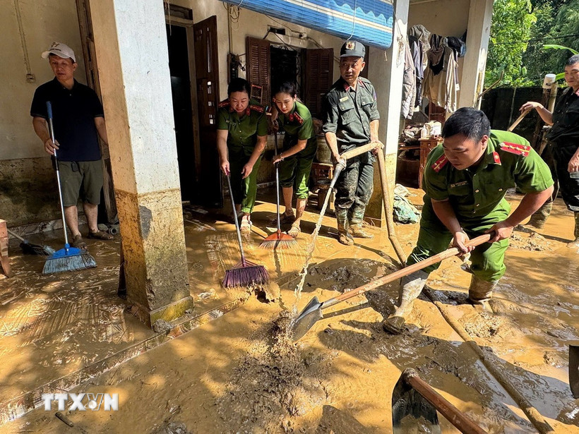 Lực lượng chức năng hỗ trợ người dân khắc phục hậu quả mưa lũ. (Ảnh: TTXVN phát)