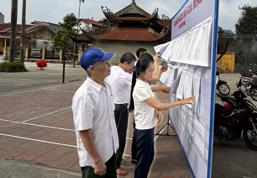 Người dân khu phố Phú Mẫn, thị trấn Chờ, huyện Yên Phong tìm hiểu các đề án sáp nhập. (Ảnh: Thái Hùng/TTXVN)