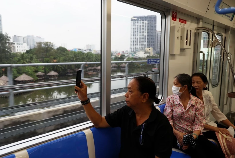 Người dân lưu lại hình ảnh đô thị bên ngoài khi trải nghiệm tuyến metro số 1. (Ảnh: Huyền Trinh/TTXVN)