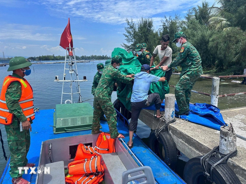 Cán bộ chiến sỹ Đồn biên phòng Tam Thanh chuyển thi thể nạn nhân vào đất liền. (Ảnh: TTXVN phát)