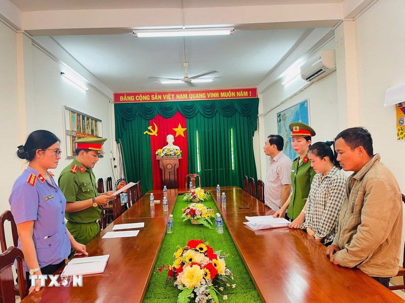 Cơ quan cảnh sát điều tra tống đạt các quyết định tố tụng đối với Trần Mỹ Tiên (áo carô). (Ảnh: TTXVN phát)