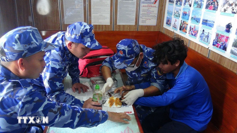 Cán bộ chiến sỹ tàu CSB 4035, Bộ Tư lệnh Vùng Cảnh sát biển 4 chăm sóc, hỗ trợ y tế cho ngư dân gặp nạn trên biển. (Ảnh: TTXVN phát)