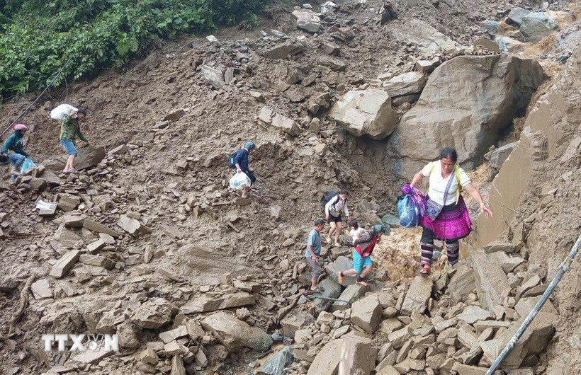 Người dân đi bộ qua khu vực sạt lở tại đèo Khau Phạ. (Ảnh: TTXVN phát)