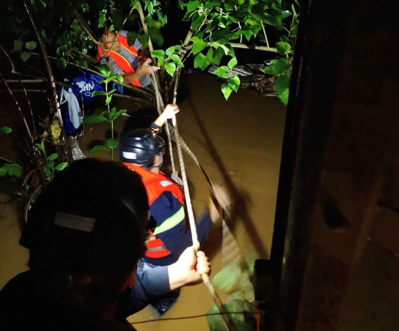 Lực lượng chức năng đu dây ra giữa dòng kênh để cứu người. (Ảnh: TTXVN phát)