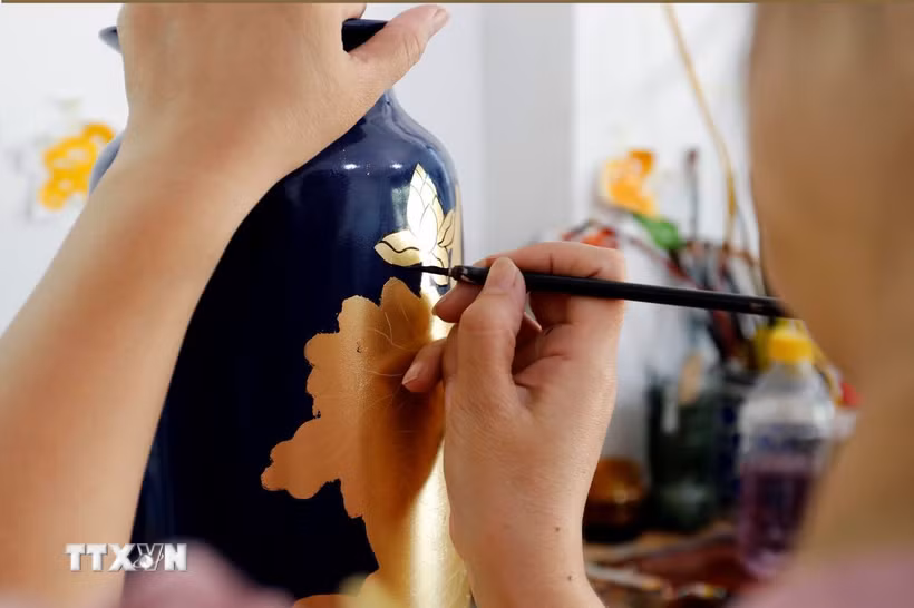 Vẽ hoa văn trên sản phẩm gốm sứ tại một cơ sở ở làng nghề Hạ Thái. (Ảnh: Trần Việt/TTXVN)