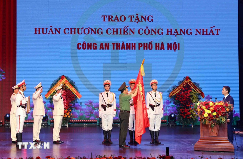 Đại tướng Lương Tam Quang, Bộ trưởng Bộ Công an gắn Huân chương Chiến công hạng Nhất lên lá cờ truyền thống của Công an thành phố Hà Nội. (Ảnh: Phạm Kiên/TTXVN)