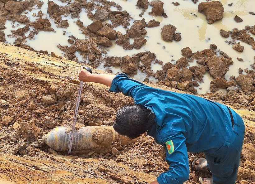 Lực lượng dân quân tự vệ thị trấn Phước Cát kiểm tra vật thể nghi là bom do người dân phát hiện khi đào hồ chứa nước. (Ảnh: TTXVN phát)