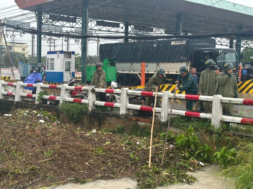 Các lực lượng được huy động để khẩn trương khơi thông dòng chảy, thu dọn lượng rác, cỏ dại và bèo tây đang gây tắc nghẽn tại các cửa cống, điểm giao của Suối Giữa. (Ảnh: Dương Chí Tưởng/TTXVN)