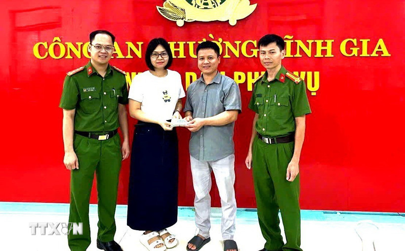 Công an phường Tĩnh Gia và chị Lê Thị Huyền trao trả lại tài sản cho người bỏ quên. (Ảnh: TTXVN phát)