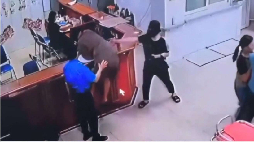 Hình ảnh người đàn ông chồm qua quầy làm thủ tục để hành hung nhân viên y tế. (Ảnh cắt từ clip)