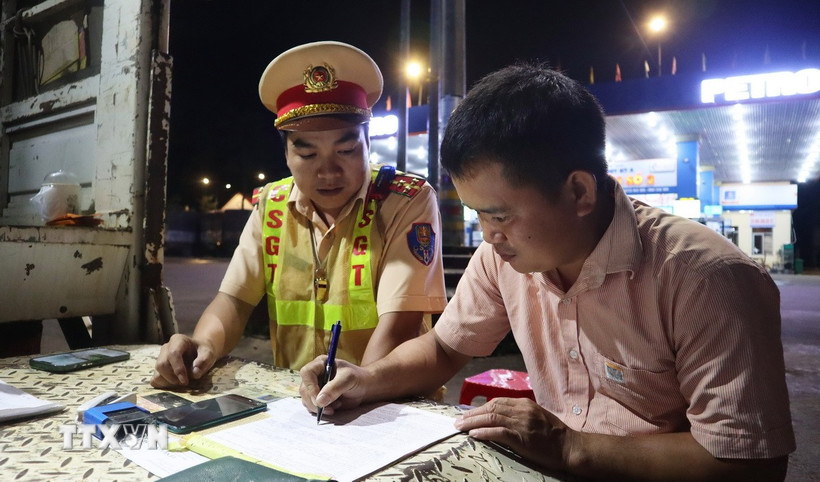 Lực lượng Cảnh sát giao thông trạm Đồng Phú lập biên bản, xử lý xe khách vi phạm giao thông. (Ảnh: Đậu Tất Thành/TTXVN)