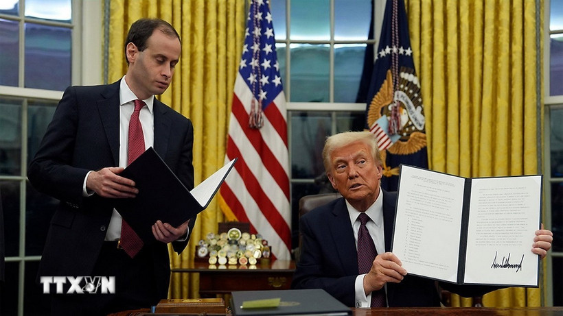 Tổng thống Mỹ Donald Trump (phải) ký sắc lệnh hành pháp ngay sau lễ nhậm chức, tại Nhà Trắng ở Washington DC., ngày 20/1/2025. (Ảnh: AP/TTXVN)