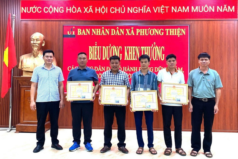Lãnh đạo Ủy ban Nhân dân xã Phương Thiện trao giấy khen cho 5 công dân. (Ảnh: TTXVN phát)