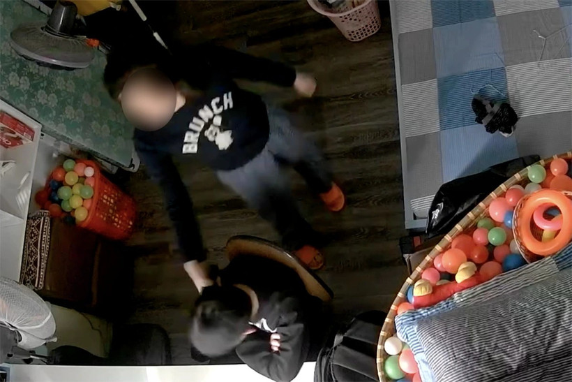 Clip ghi lại cảnh một phụ nữ cầm điện thoại đánh vào đầu bé trai, bắt bé đứng. (Ảnh chụp màn hình)