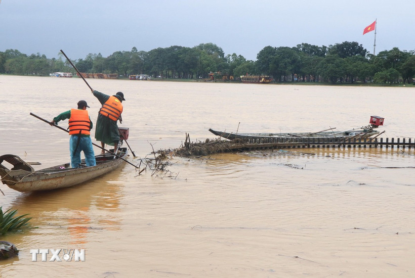 Công nhân dọn rác do lũ cuốn dạt vào bờ Nam sông Hương, thành phố Huế sáng 2/11. (Ảnh: Nguyên Lý /TTXVN)