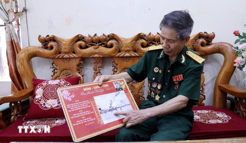 Cựu chiến binh Nguyễn Thế Liêm giới thiệu về bức ảnh 'Truy kích địch trong sân bay Tân Sơn Nhất.' (Ảnh: Quang Cường/TTXVN)
