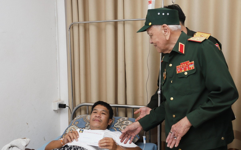 Thiếu tướng Võ Văn Chót, Trưởng ban danh dự Ban Liên lạc quân tình nguyện và chuyên gia quân sự Việt Nam giúp cách mạng Lào tỉnh Nghệ An, trao quà cho thương binh nặng đang điều trị tại Bệnh viện Trung ương Quân đội 103 Lào. (Ảnh: Xuân Tú/TTXVN)
