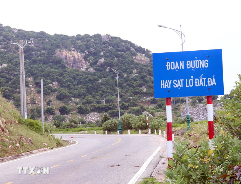 Lực lượng chức năng gắn biển cảnh báo tuyến đường hay xảy ra sạt lở để người và phương tiện thận trọng khi qua tuyến đường ven biển. (Ảnh: Công Thử/TTXVN)