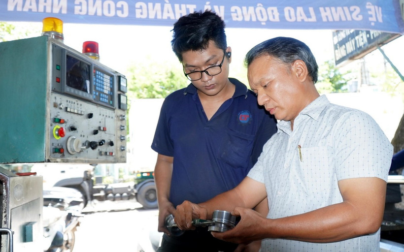 Ông Lê Tấn Thêm (ngoài cùng, bên phải) hướng dẫn thợ chế tạo những thiết bị công nghệ ứng dụng cho tàu cá. (Ảnh: Lê Phước Ngọc/TTXVN)