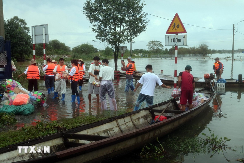 Các đoàn tình nguyện vận chuyển hàng hóa lên ghe để đưa vào những vùng ngập sâu ở thành phố Huế. (Ảnh: Đỗ Trưởng/TTXVN)