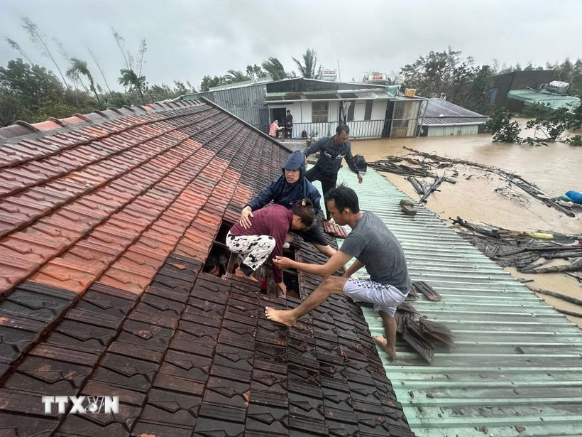 Lũ dâng cao, người dân phải phá mái nhà leo lên để tránh nguy hiểm. (Ảnh: TTXVN phát)