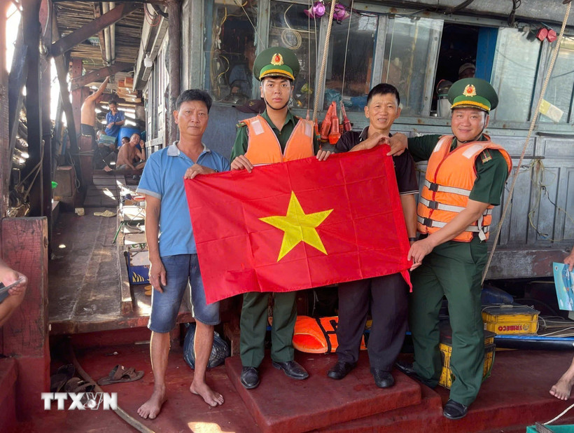 Hội viên Nghiệp đoàn nghề cá, tổ viên tổ đoàn kết trên biển thành phố Đà Nẵng nhận cờ Tổ quốc do Đồn biên phòng cửa khẩu cảng Kỳ Hà trao tặng. (Ảnh: Đoàn Hữu Trung/TTXVN)