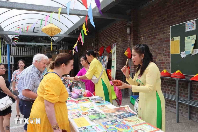 Bàn bè Bỉ mua các sản vật Việt Nam ủng hộ gây quỹ hỗ trợ trẻ em nghèo tỉnh Bắc Giang. (Ảnh: Hương Giang/TTXVN)