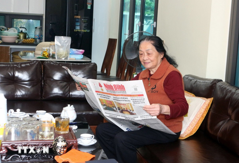 Đảng viên Vũ Thị Tuyết, thôn Chằm Vải, xã Thanh Bình, theo dõi thông tin về công tác chuẩn bị Đại hội Đảng XIV trên báo chí. (Ảnh: Nguyễn Chinh/TTXVN)