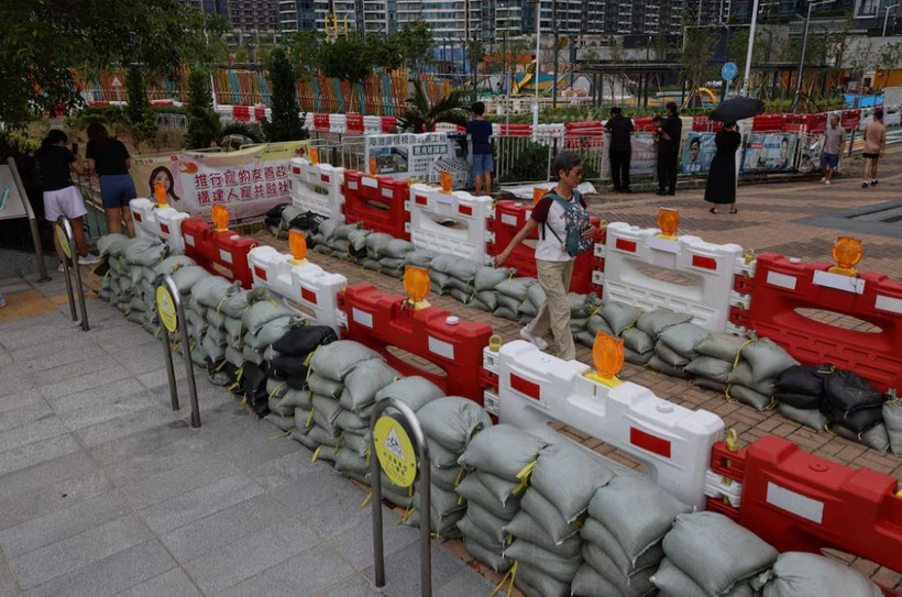 Người dân đi ngang qua những bao cát được đặt để ngăn lũ lụt do siêu bão Ragasa gây ra. (Nguồn: Reuters)