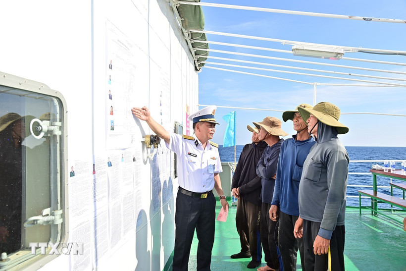 Đại tá Lê Hồng Quang, Phó Chủ nhiệm Chính trị Vùng 2 Hải quân, Tổ trưởng Tổ bầu cử sớm trên biển hướng dẫn cho ngư dân tàu cá QNg 96435 TS nắm thể lệ bầu cử. (Ảnh: TTXVN phát)