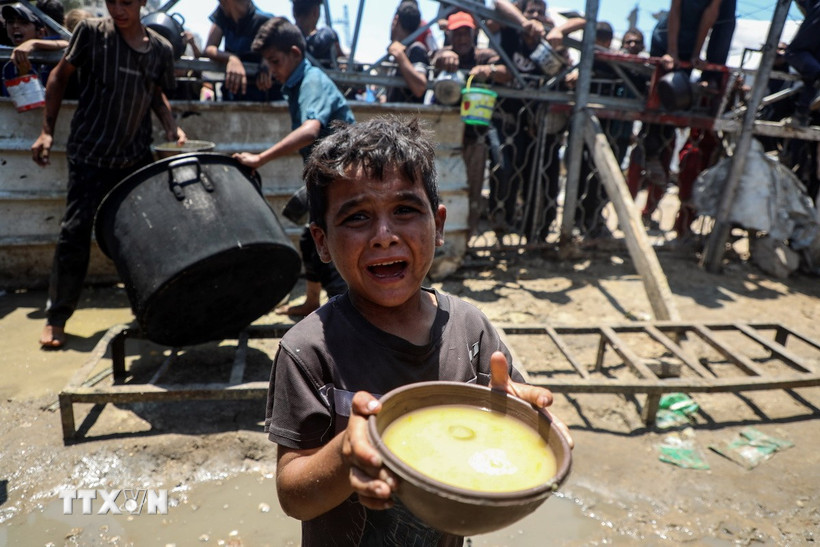 Em nhỏ Palestine nhận thức ăn cứu trợ tại thành phố Gaza, ngày 24/7/2025. (Ảnh: THX/TTXVN)