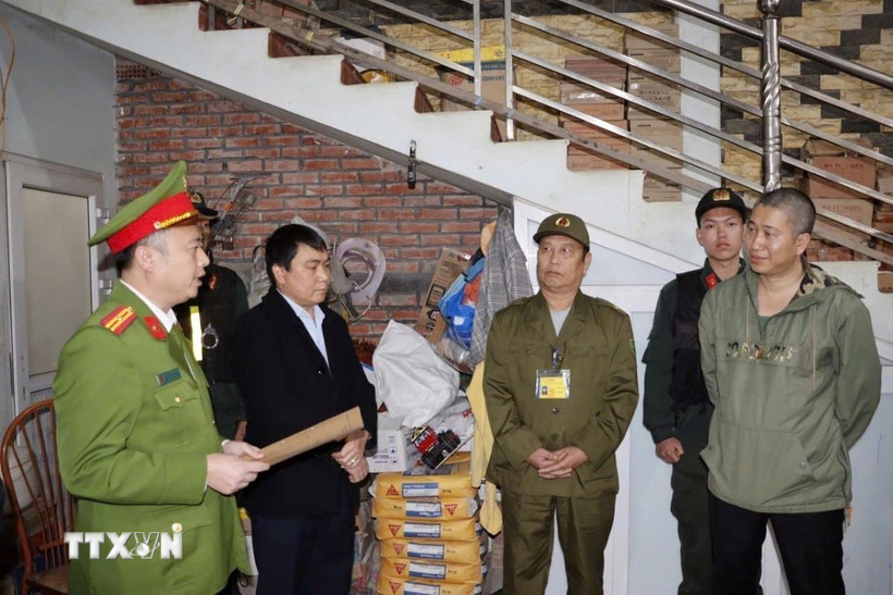 Cơ quan cảnh sát đọc lệnh khởi tố đối tượng Trần Minh Bảo (ngoài cùng bên phải) về tội “Vu khống”. (Ảnh: TTXVN phát.)