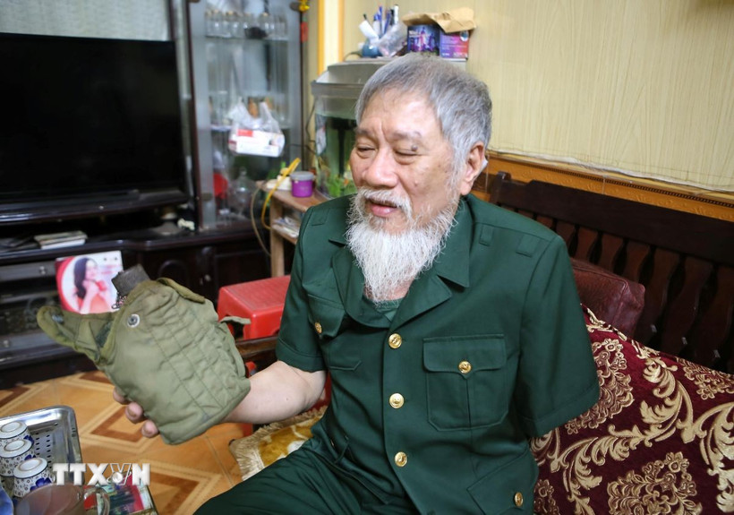 Ông Nguyễn Thế Tám nâng niu chiến tích tịch thu được của quân địch trong thời gian tham gia giải phóng Sài Gòn. (Ảnh: Công Luật/TTXVN)