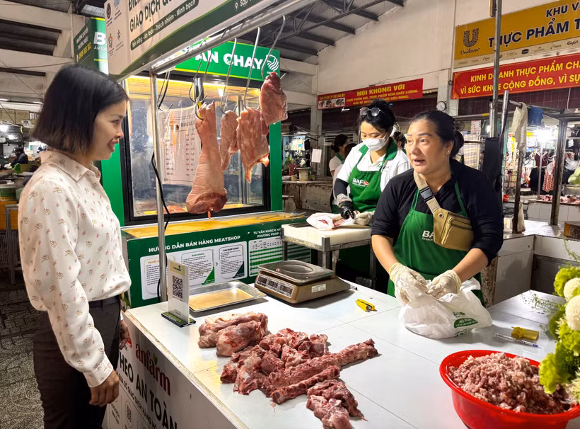 Đại diện phường Tân Mỹ trò chuyện với tiểu thương tham gia bán thịt "Tick xanh trách nhiệm" tại chợ Tân Mỹ, Thành phố Hồ Chí Minh. (Ảnh: Hương Giang/TTXVN)