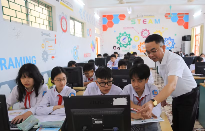 Thầy Nguyễn Chí Thanh, Giáo viên Trường THCS Nguyễn Bỉnh Khiêm, xã Vĩnh Bảo hướng dẫn học sinh làm bài tập môn Tin học. (Ảnh: Minh Thu/TTXVN)