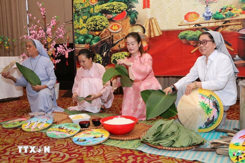 Các sơ cùng đại diện cộng đồng mô phỏng nét đẹp gói bánh chưng tại buổi lễ. (Ảnh: TTXVN phát)