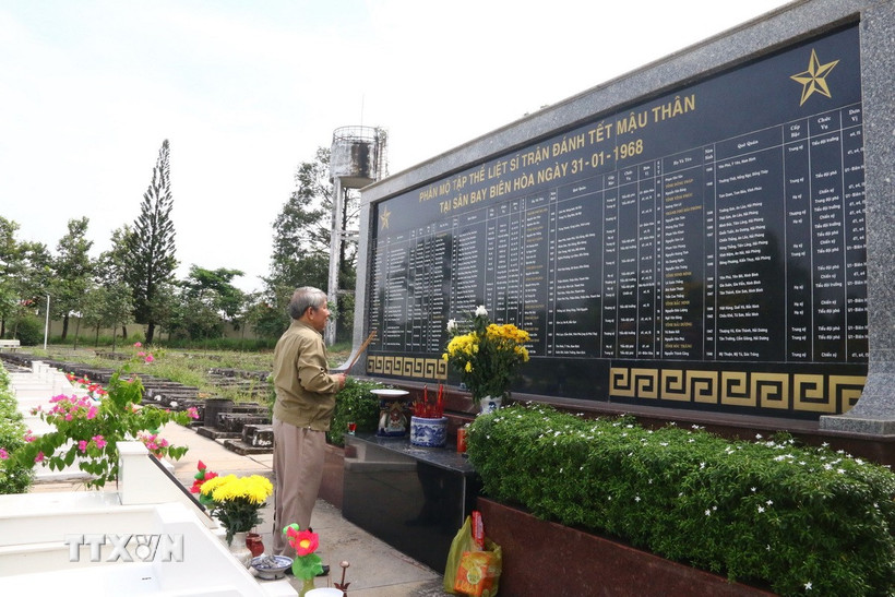 Cựu chiến binh thắp nén nhang cho đồng đội bên phần mộ tập thể liệt sỹ trong trận đánh Tết Mậu Thân tại Sân bay Biên Hòa năm 1968 tại Nghĩa trang Liệt sỹ tỉnh Đồng Nai. (Ảnh: Lê Xuân/TTXVN)