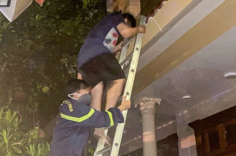 Người bị nạn được lực lượng chức năng hỗ trợ thoát khỏi ngôi nhà qua thang. (Ảnh: Công an cung cấp)