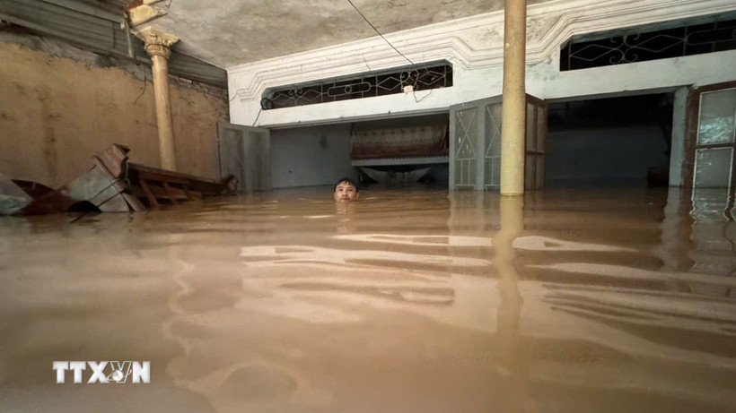 Ông Lê Bình (thôn Cửa Hà, xã Cẩm Thủy, Thanh Hóa) phải bơi trong ngôi nhà bị ngập sâu gần 2m để cố vớt vát các tài sản còn lại. (Ảnh: Việt Hoàng/TTXVN)