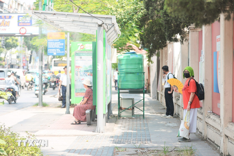Quạt, khăn ướt phủ đầu...là cách của người dân chọn khi đợi xe buýt. (Ảnh: Lê Đông/TTXVN)