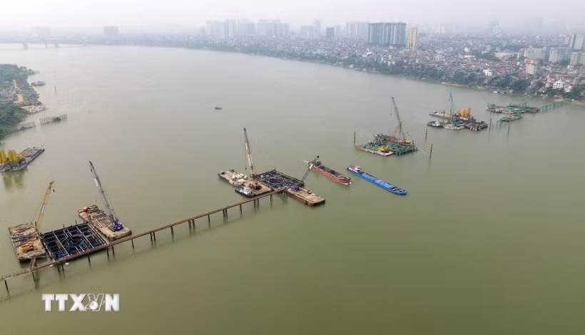 Tranh thủ thời tiết thuận lợi đầu năm, các nhà thầu thi công cầu Trần Hưng Đạo vượt sông Hồng đang huy động tối đa nhân lực, máy móc, tổ chức nhiều mũi thi công song song, quyết tâm bám “đường găng” tiến độ để đưa công trình về đích đúng cam kết. (Ảnh: Quốc Khánh/TTXVN)