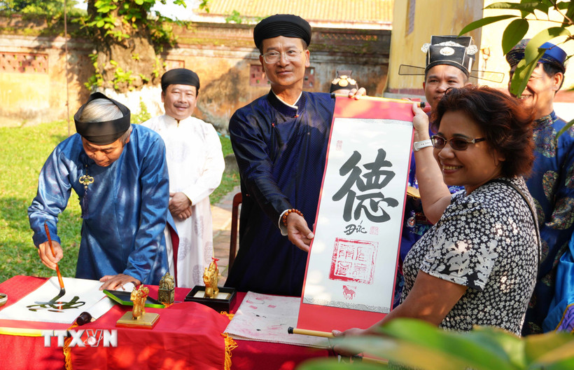 Du khách được tặng chữ thư pháp đầu năm mới Bính Ngọ ở Thế Miếu, Đại Nội Huế. (Ảnh: Nguyên Lý/TTXVN)