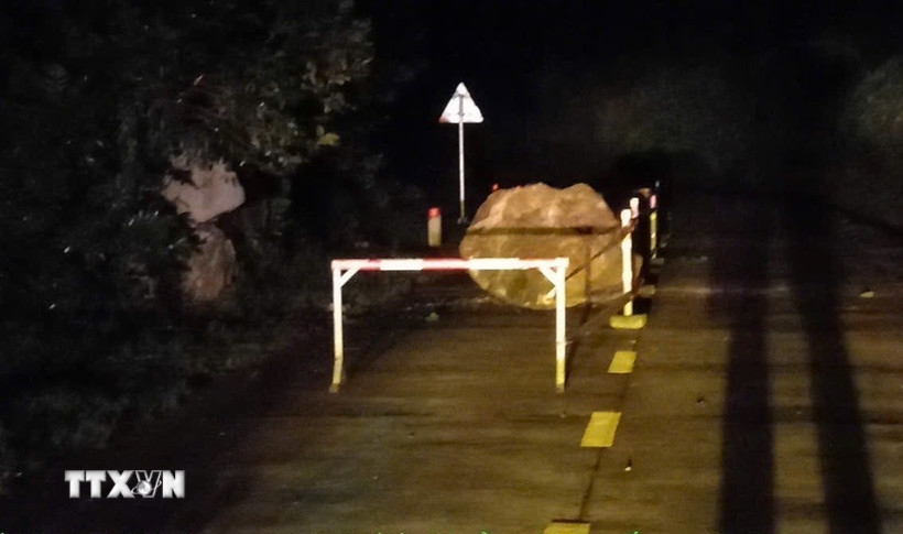 Tảng đá lớn lăn xuống từ vách núi, nằm chắn một phần mặt đường Hồ Chí Minh nhánh Tây. (Ảnh: TTXVN phát)