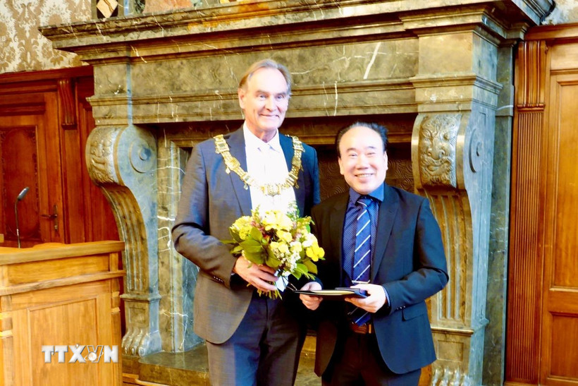 Ông Burkhard Jung, Thị trưởng thành phố Leipzig trao tặng huy hiệu, bảng vàng danh dự, bằng khen của Thành phố Leipzig cho ông Bùi Quang Huy - Chủ tịch Hội người Việt tại thành phố Leipzig. (Ảnh: Phương Hoa/TTXVN)