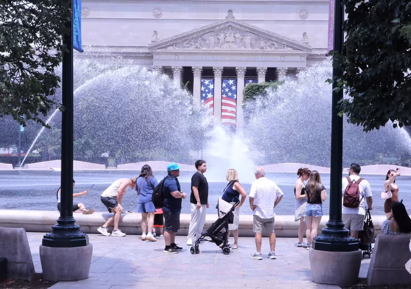 Du khách tránh nắng nóng bên đài phun nước tại khu vực National Mall (Quảng trường Quốc gia) ở thủ đô Washington D.C. (Ảnh: Ngọc Quang/TTXVN)