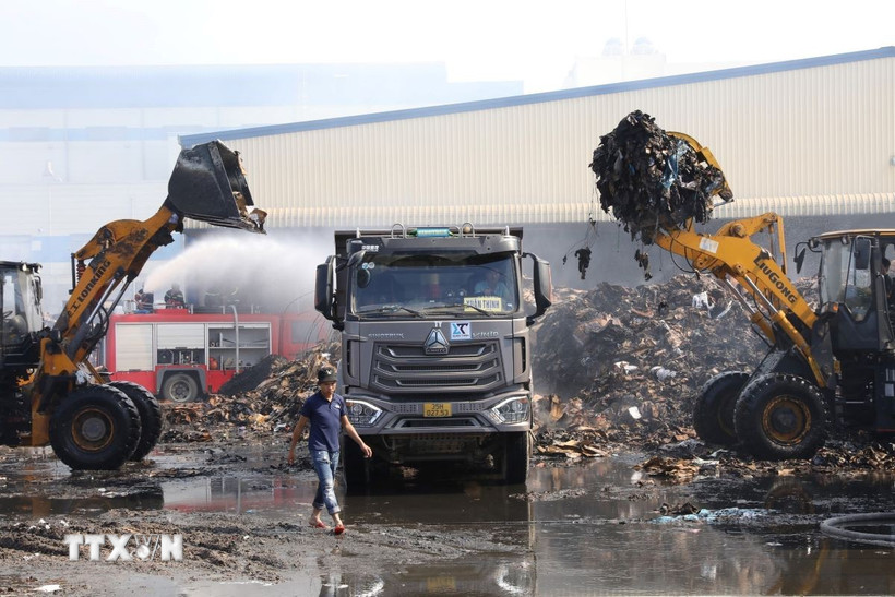Các lực lượng dập tắt đám cháy thành công, tiến hành vận chuyển nguyên vật liệu và tàn tro ra ngoài khu vực tập kết. (Ảnh: Đức Phương/TTXVN)