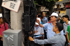 Trưởng đoàn thanh tra Nguyễn Văn Minh (đội mũ) kiểm tra sai sót của doanh nghiệp trong quá trình lắp đặt đường dây, cáp đi nổi. (Ảnh: T.H/Vietnam+)