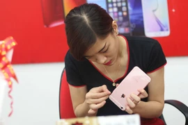 Dán bảo vệ cho siêu phẩm của "quả táo" tại FPT Shop. (Ảnh: Trung Hiền/Vietnam+)