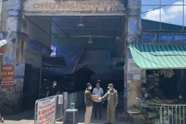 Kiểm tra thẻ của người dân đến chợ Nhật Tân (Nhật Tân, Tây Hồ). (Ảnh: Mạnh Khánh/Vietnam+)